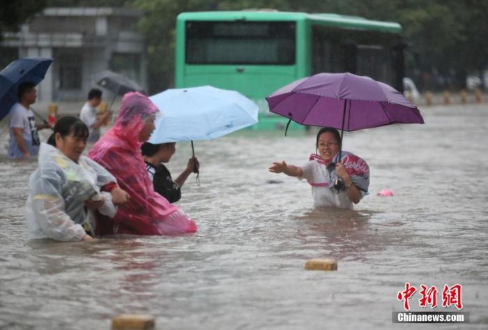 7月20日，鄭州遭遇強(qiáng)降雨，在經(jīng)三路、農(nóng)業(yè)路上，市民互相幫助走在齊腰深的積水里。 圖片來源：視覺中國